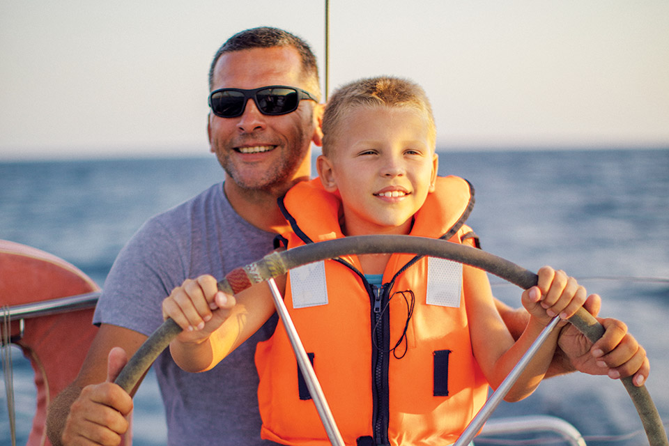 Child and dad behind the wheel of a boat