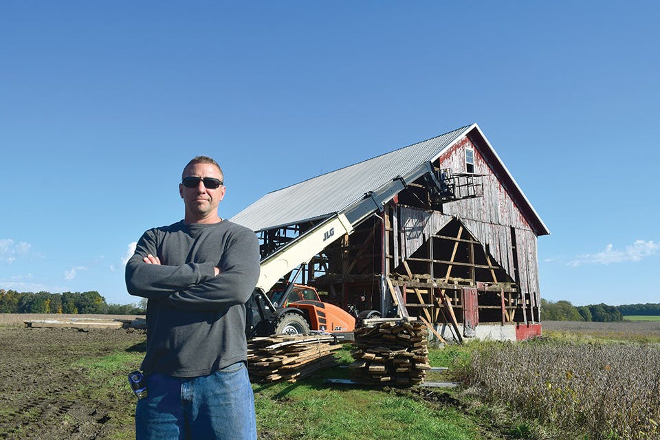 Matt Gleckler photographed in front of a barn Antique Beams & Boards is disassembling