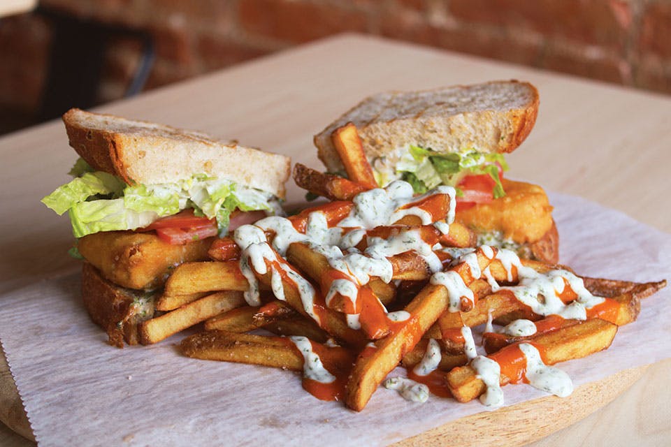 Fish sandwich and fries with ranch dressing and Buffalo sauce