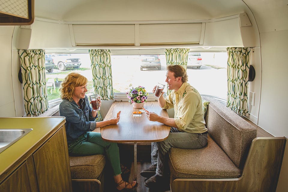 Man and woman playing cards at a table inside one of the Argosy trailers in Coshocton (photo courtesy of Ben Croghan)