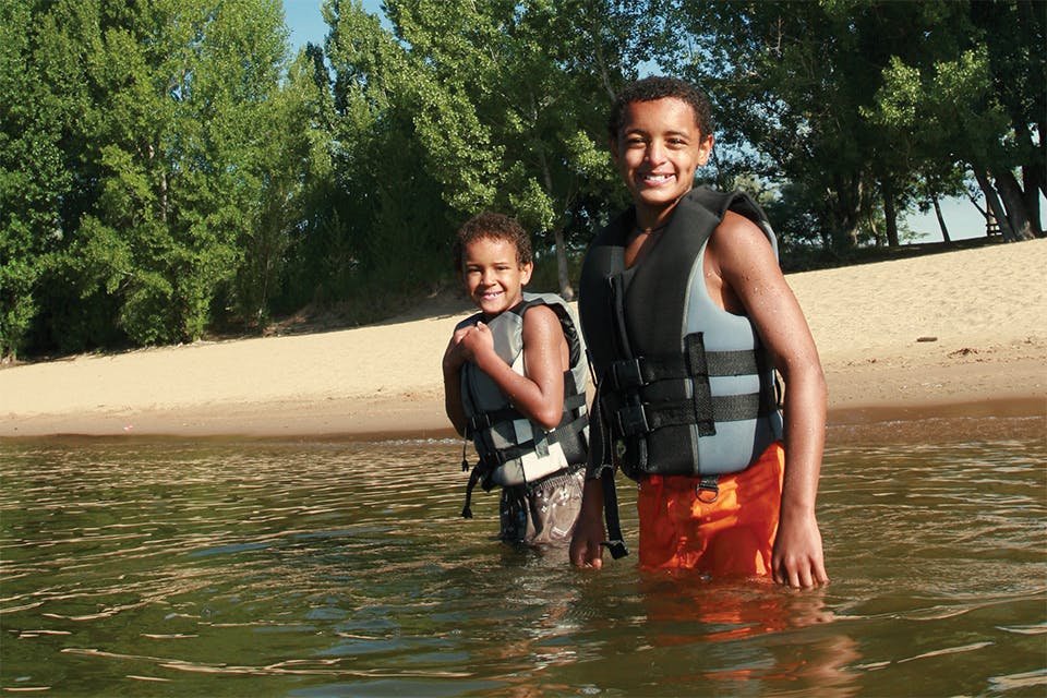 Two boys with lifejackets in shallow water (photo by iStock)