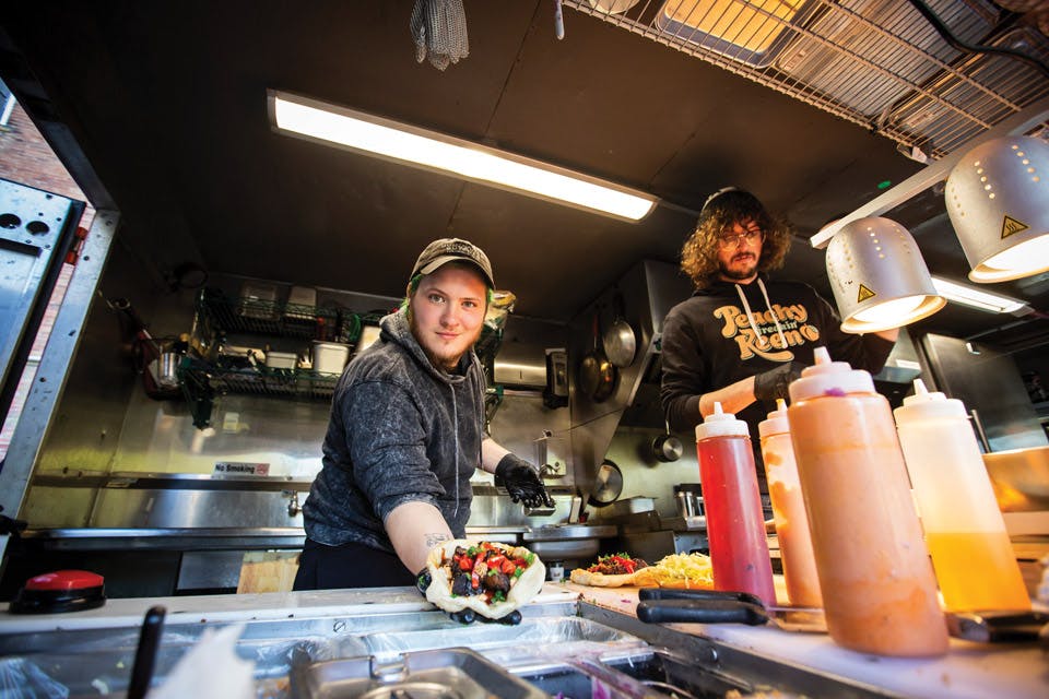 Man holding food out at Ray Ray’s Reload food truck window in Columbus (photo by Chris Casella)