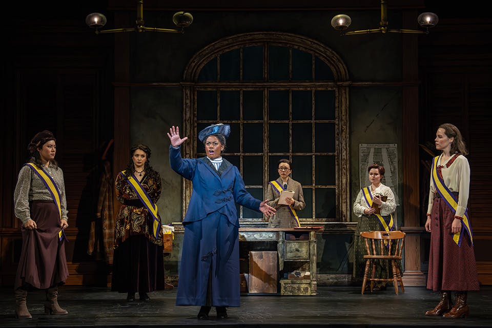 Woman standing on stage giving speech during Suffs (photo by Joan Marcus)